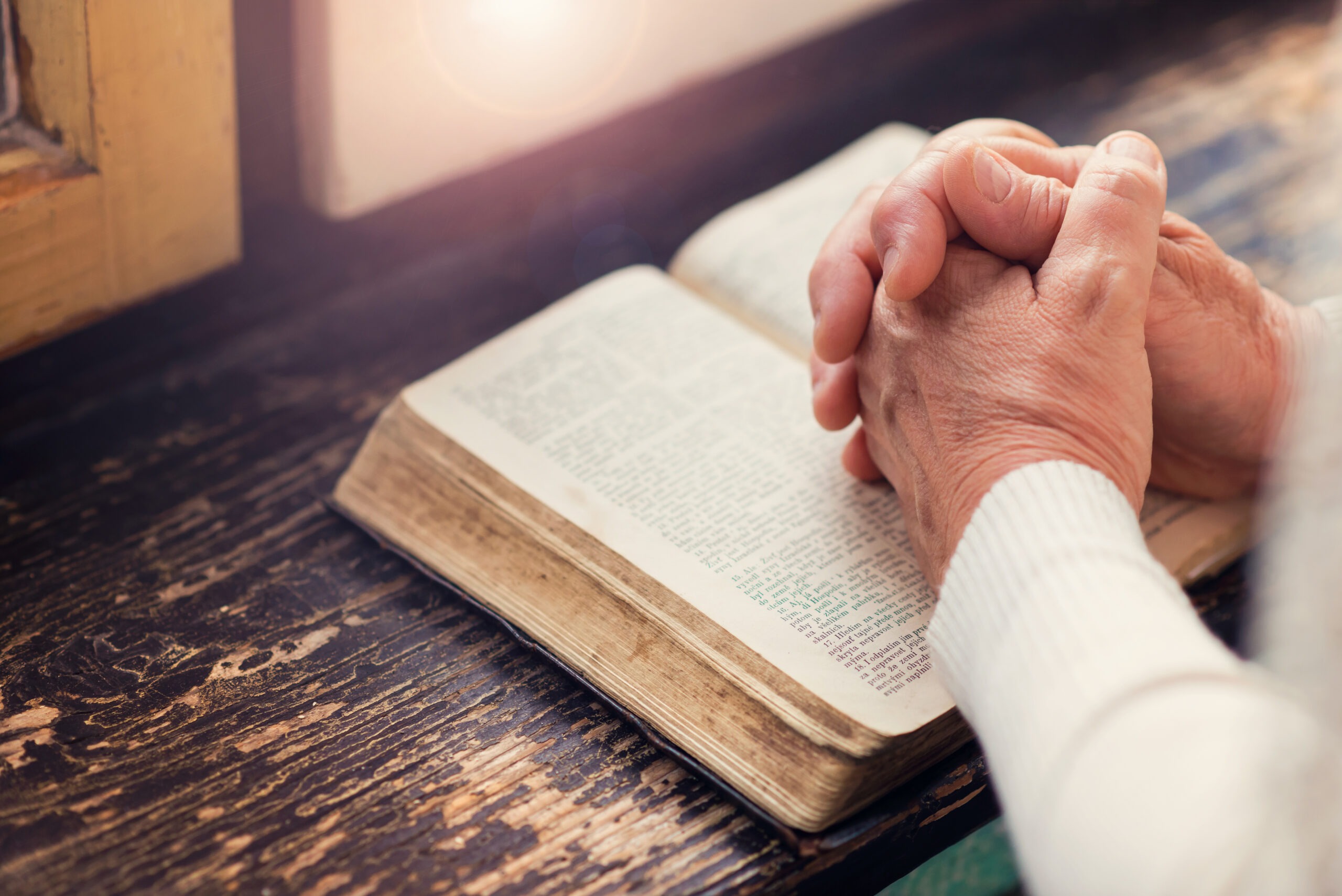 Elderly man praying with bible
